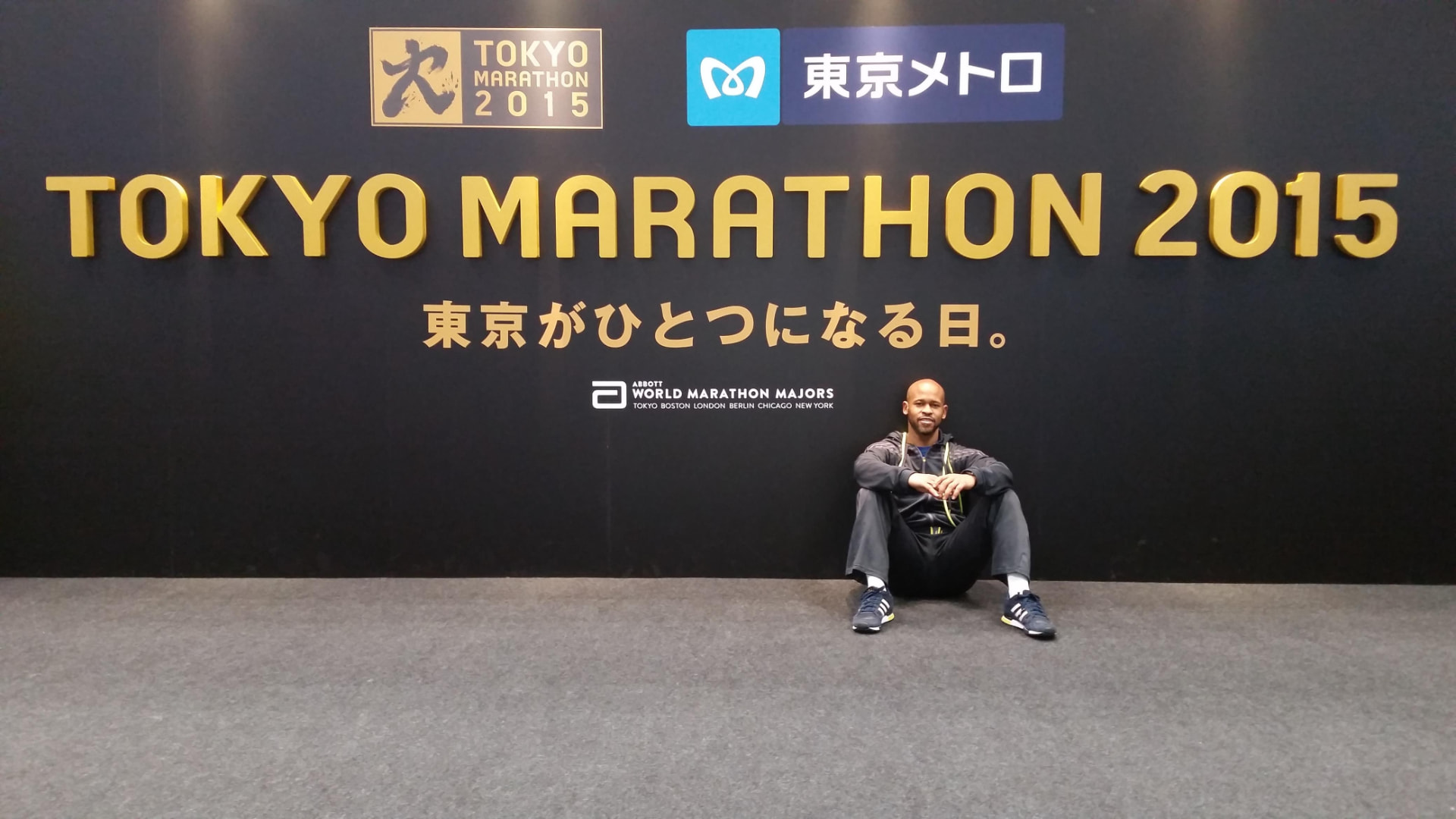 Gary Purdy seated beneath the Tokyo Marathon 2015 wall at the race expo